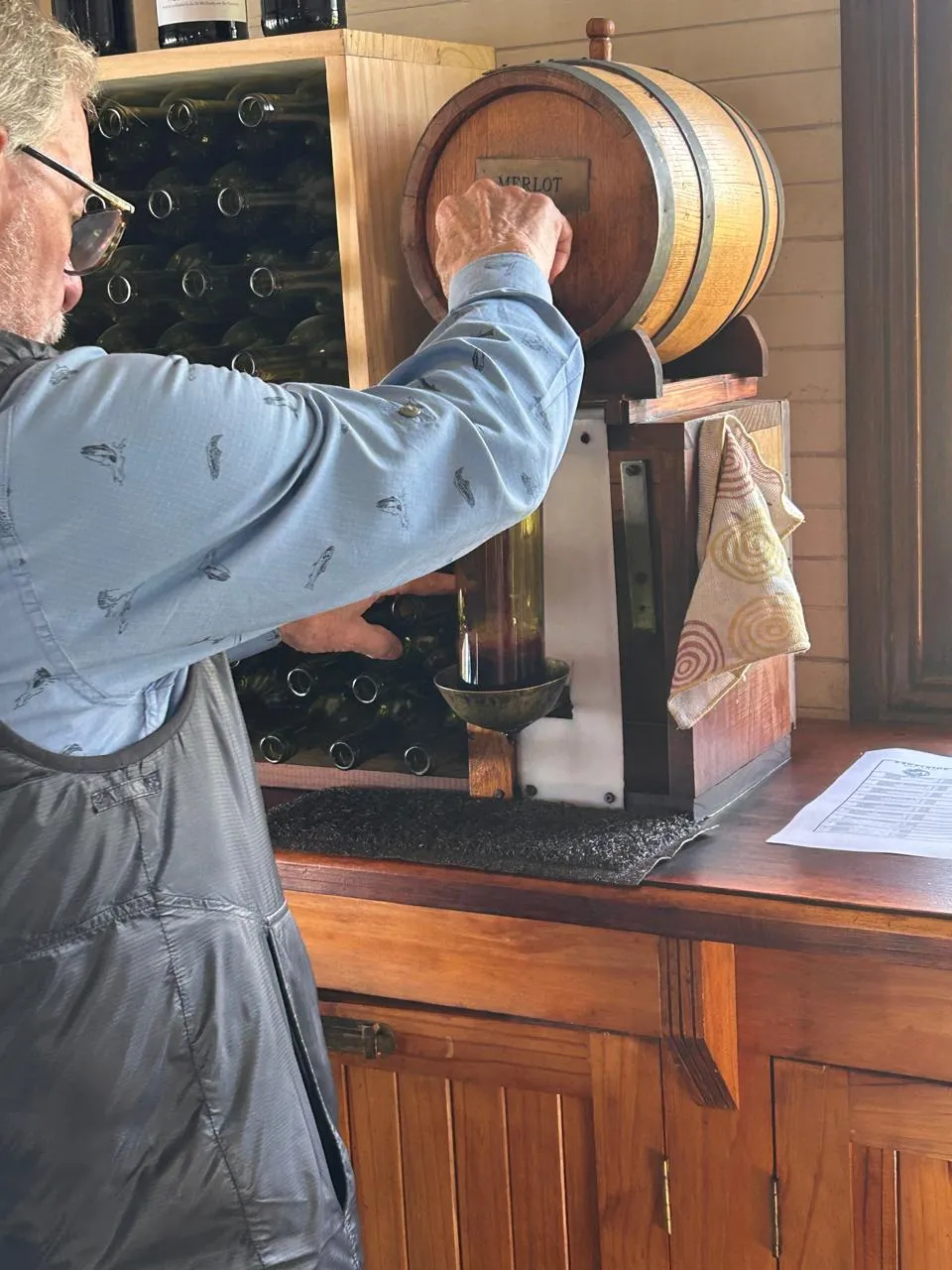 A guest drawing Merlot from a wooden barrel to blend his own bottle at Excelsior wine estate